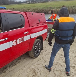 policjant i strażacy podczas wodowania łodzi