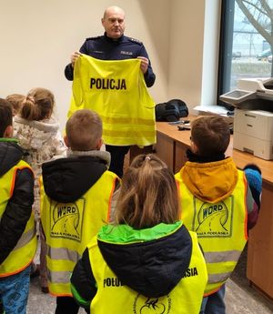 policjant prezentuje dzieciom kamizelki opowiadając o bezpieczeństwie