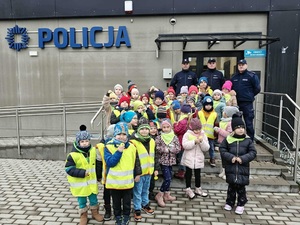 wspólne zdjęcie policjantów i dzieci przed budynkiem posterunku