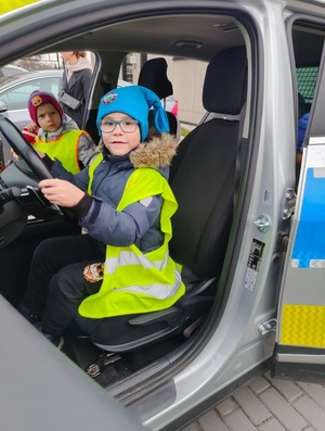 dziecko siedzi za kierownicą radiowozu