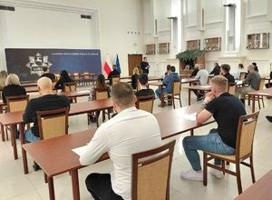 kandydaci do służby w policji siedzą przy stolikach podczas rozwiązywania testu