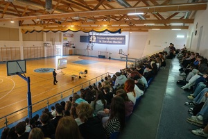 uczestnicy prelekcji siedzą na trybunach hali sportowej podczas spotkania