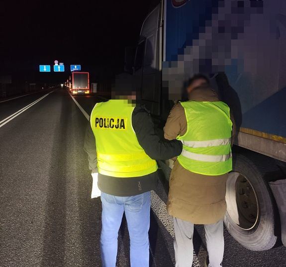 policjant idzie z zatrzymanym mężczyzną