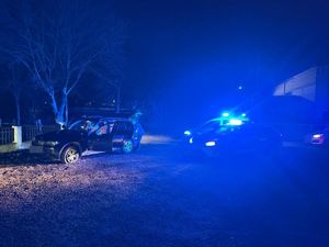 policjant przeszukuje samochód, po prawej stronie zaparkowane są radiowozy