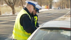 policjanci ruchu drogowego stoją przy radiowozie
