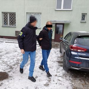 policjant prowadzi zatrzymanego mężczyznę