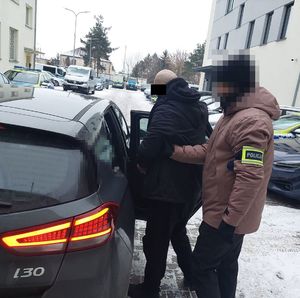 policjant doprowadza zatrzymanego