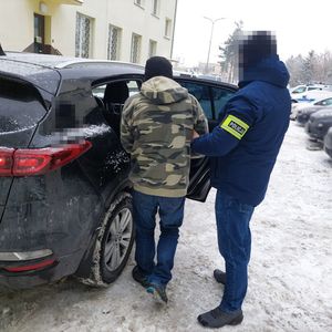 policjant wprowadza zatrzymanego do radiowozu