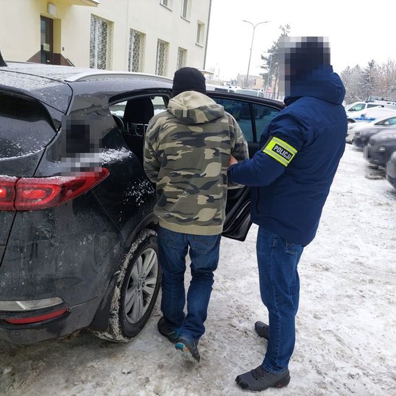 policjant wprowadza zatrzymanego do radiowozu