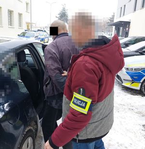 policjant wprowadza zatrzymanego do radiowozu
