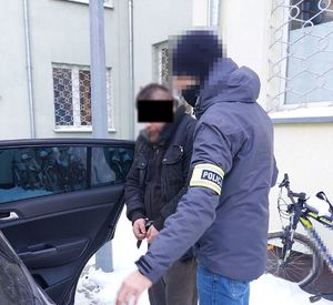 policjant wprowadza zatrzymanego mężczyznę do radiowozu