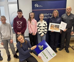 uczestnicy spotkania. Policjantka trzyma w rękach otrzymane podziękowania