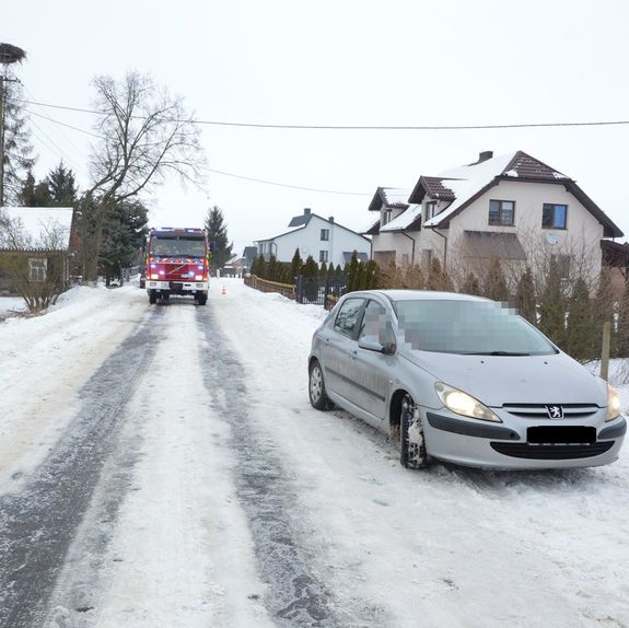 samochód stojący na drodze oraz pojazd straży pożarnej