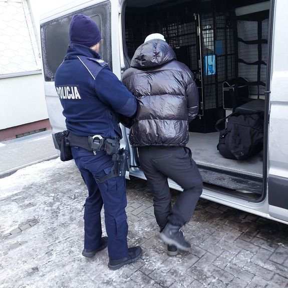 policjant wprowadza zatrzymanego