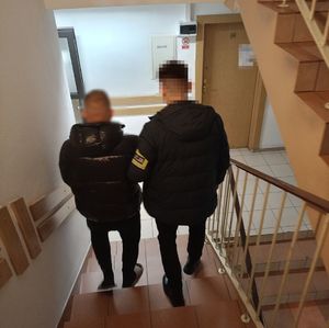 policjant prowadzi zatrzymanego po schodach