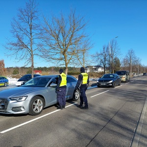 policjanci stoją przy samochodzie osobowym. Jeden kontroluje trzeźwość kierowcy