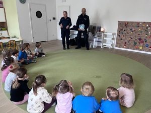 policjanci rozmawiają z dziećmi siedzącymi w kółku.