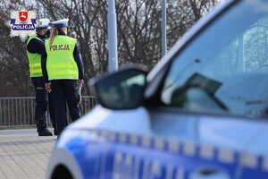Policjanci wydziału ruchu drogowego przy oznakowanym radiowozie