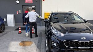 Nieumundurowany policjant prowadzi zatrzymanego do radiowozu