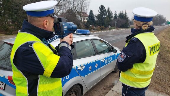 policjanci wydziału ruchu drogowego. Policjant stoi z laserowym miernikiem predkości