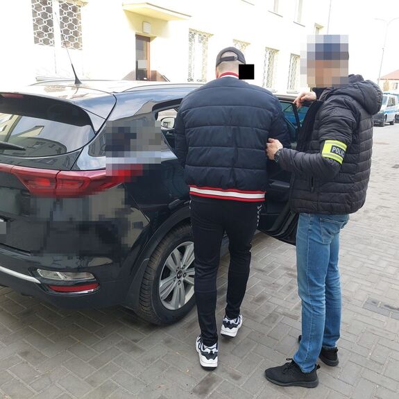 policjant prowadzi zatrzymanego do radiowozu