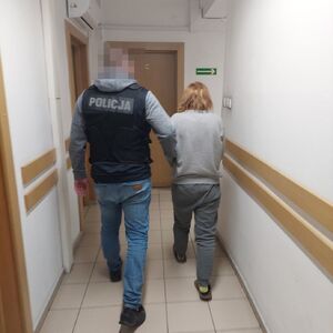 policjant w kamizelce z napisem policja prowadzi zatrzymaną