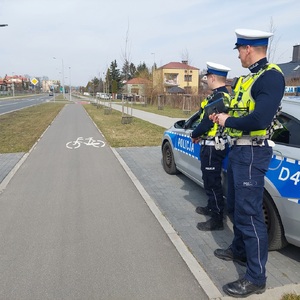 policjanci ruchu drogowego przy radiowozie monitorują sytuację na drodze