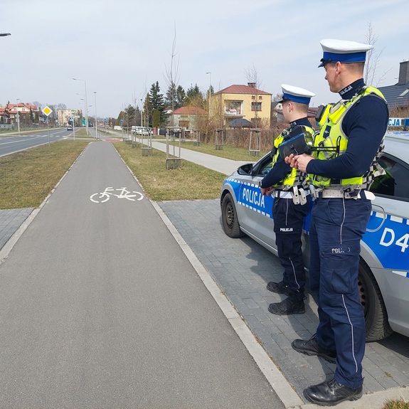 policjanci ruchu drogowego przy radiowozie monitorują sytuację na drodze