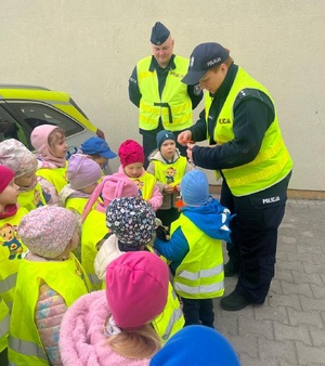 policjantka przekazuje dzieciom elementy odblaskowe.