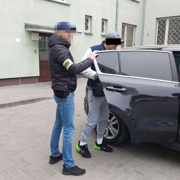 policjant wprowadza zatrzymanego mężczyznę do radiowozu