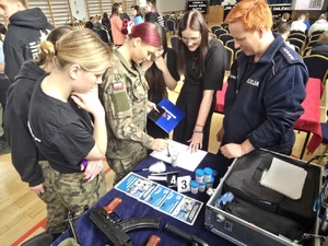 policjantka z uczniami podczas prezentacji sposobu ujawniania odbitek linii papilarnych