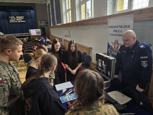 policjant rozmawiający z młodzieżą przy stoisku.