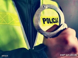 fragment zdjęcia policjanta w kamizelce odblaskowej trzymającego kajdanki w ręku