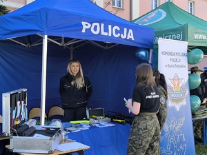 policjantka rozmawia z uczennicami odwiedzającymi stoisko.