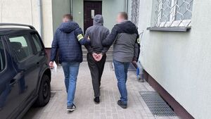 dwóch nieumundurowanych policjantów prowadzi zatrzymanego męzczyznę