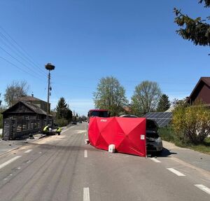 miejsce zdarzenia drogowego, policjanci obok leżącego motocykla, czerwony parawan obok samochodu osobowego