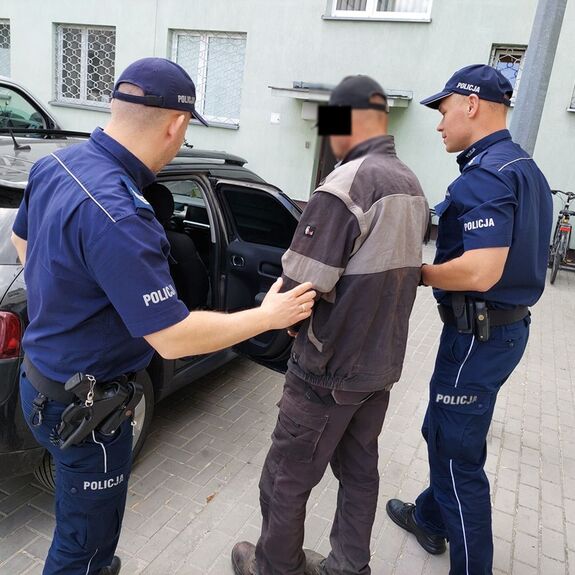policjanci wprowadzają mężczyznę do radiowozu