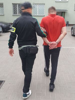 policjant prowadzi zatrzymanego