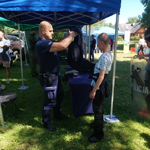 policjant pomaga dziecku założyć kamizelkę.