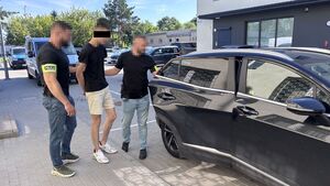 nieumundurowani policjanci prowadzący do radiowozu zatrzymanego męzczynę