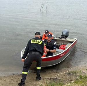 policjant i strażacy podczas wodowania łodzi