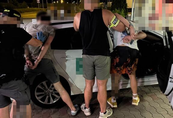 Policjanci zatrzymują mężczyzn podejrzanych o oszustwo.