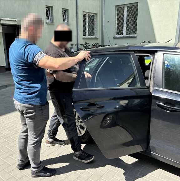 policjant wprowadza zatrzymanego do radiowozu