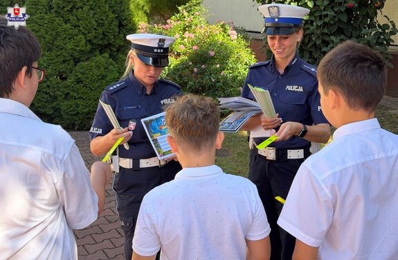 policjantki rozdają odblaski dzieciom przed szkołą"