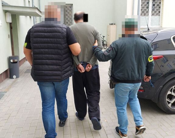 policjanci prowadzą zatrzymanego mężczyznę