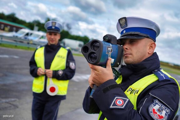 policjanci ruchu drogowego. Jeden trzyma laserowy miernik prędkości