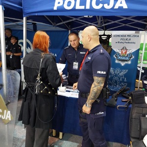 policjant rozmawia z osobą odwiedzającą policyjne stoisko.