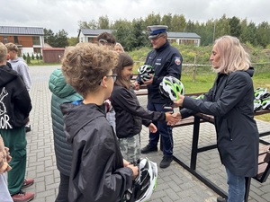 policjant i pracownik kuratorium oświaty podczas przekazani kasków