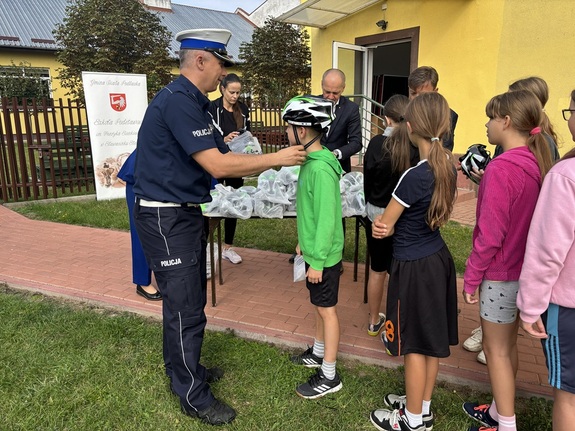 policjant przekazuje kaski dzieciom