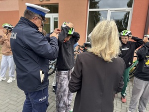 policjant pomaga dziecku nałożyć kask